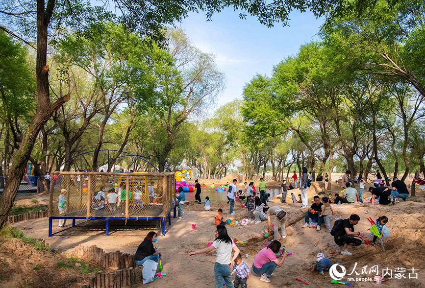 5月2日，家长陪伴孩子在呼和浩特市玉泉区“林下空间”亲子园的人造沙滩上玩沙子。丁根厚摄